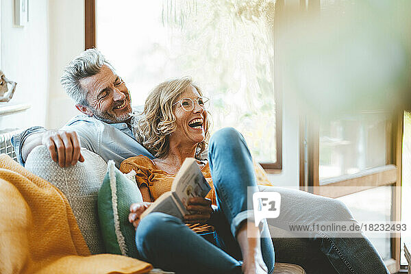 Fröhliches älteres Paar sitzt zu Hause auf dem Sofa