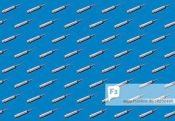 Pattern of rows of syringes flat laid against blue background