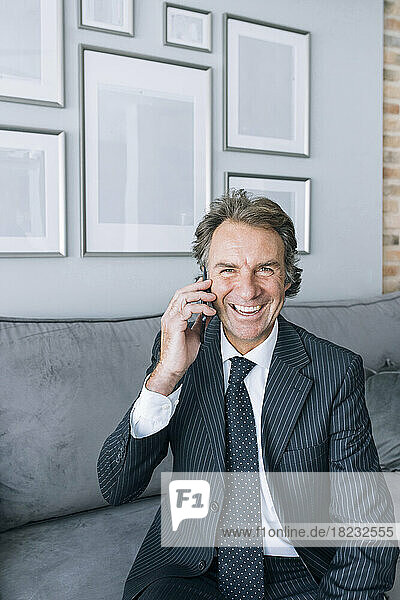 Happy mature businessman talking on mobile phone at home