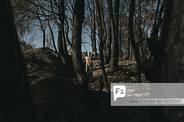 Woman standing amidst burnt trees in forest