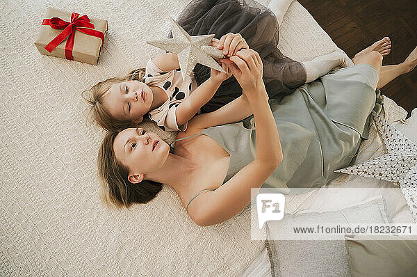 Mutter und Tochter spielen zu Hause im Bett mit dem Weihnachtsstern
