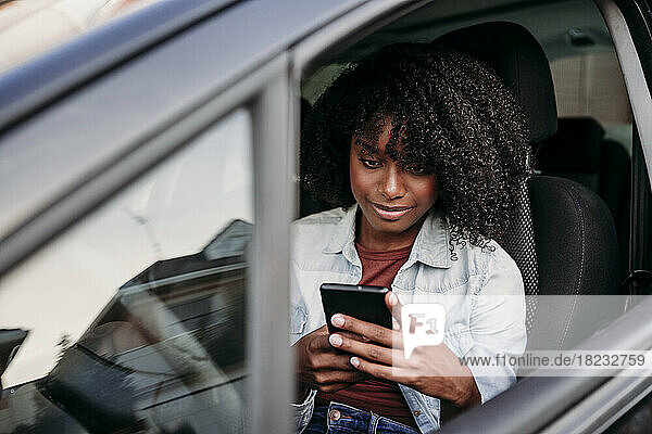 Woman using smart phone sitting in car