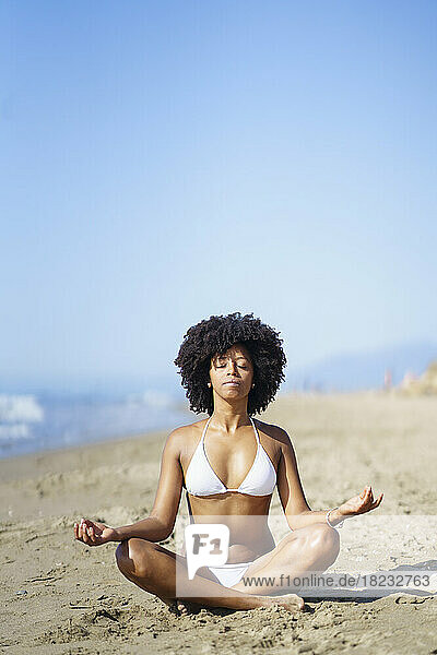 Young woman with eyes closed practicing yoga at beach
