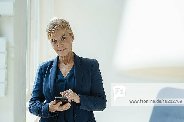 Businesswoman with smart phone at work place