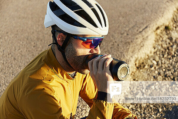 Thirsty cyclist drinking water on sunny day