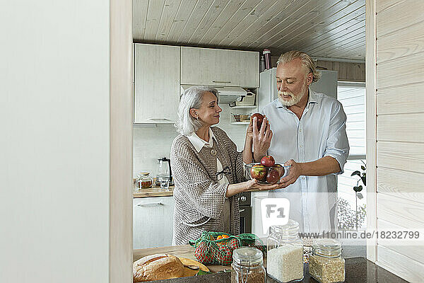 Älteres Paar hält frische Äpfel in der Küche