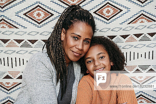 Smiling mature woman with daughter in front of patterned backdrop