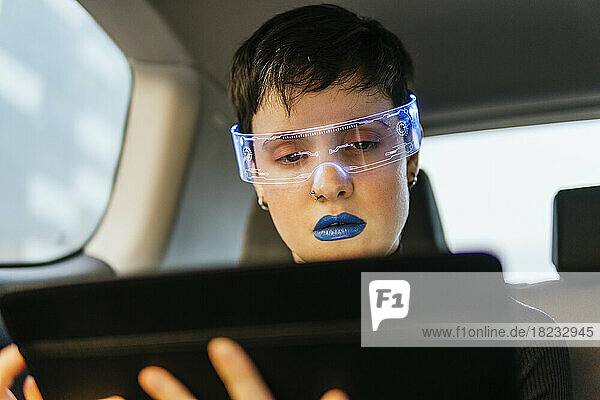 Woman wearing smart glasses using tablet PC in car