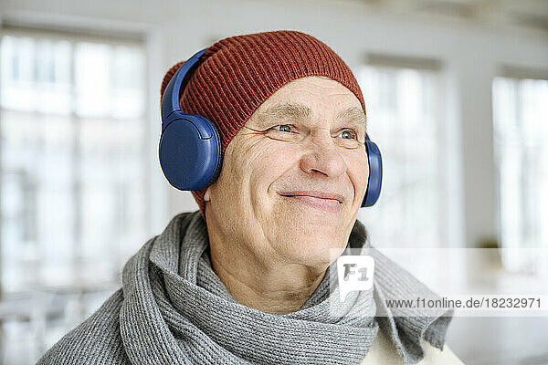 Contemplative man listening to music through headphones at home
