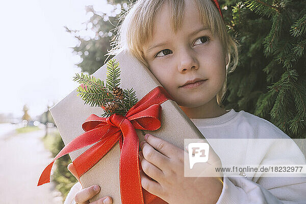 Thoughtful girl holding Christmas gift box