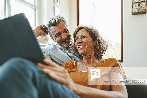 Happy mature man and woman using tablet PC in living room