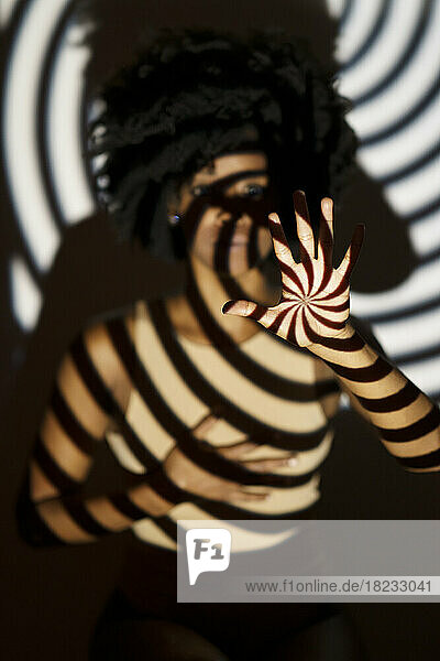 Spiral pattern shadow on woman in front of wall