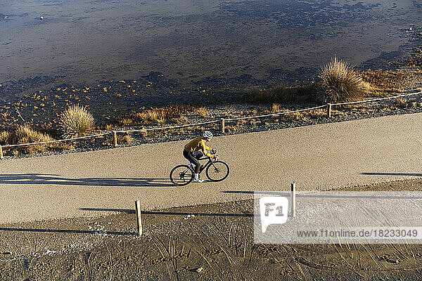 Junger Radfahrer fährt an einem sonnigen Tag mit dem Fahrrad am Strand entlang