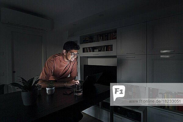 Glücklicher Mann benutzt Laptop im Wohnzimmer zu Hause