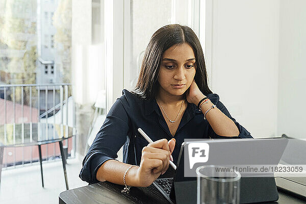 Frau lernt zu Hause mit Tablet-PC am Tisch