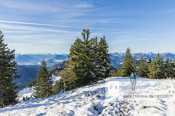 Germany  Bavaria  Female hiker walking through snow-covered mountaintop in Chiemgau Alps