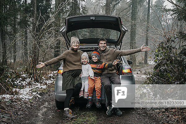 Happy family spending time together sitting in car trunk