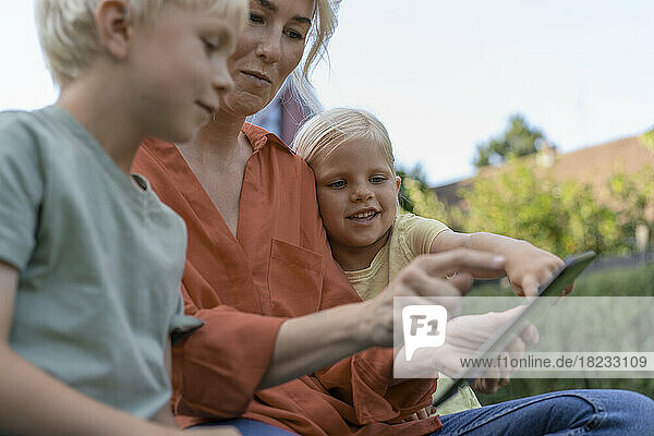 Woman using tablet PC sitting with children
