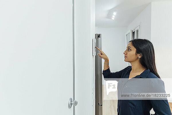 Young woman using smart home device on wall