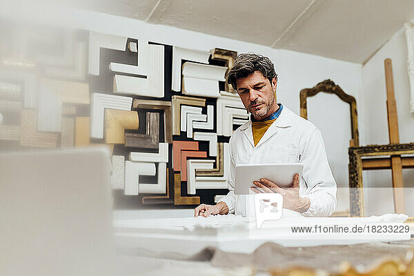 Mature craftsman using tablet PC in workshop