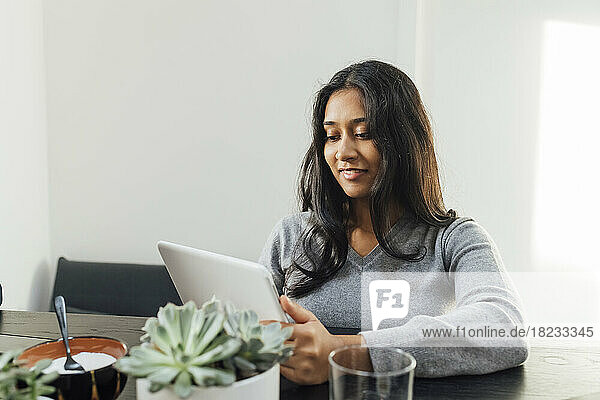 Lächelnde junge Frau  die zu Hause mit einem Tablet-PC lernt