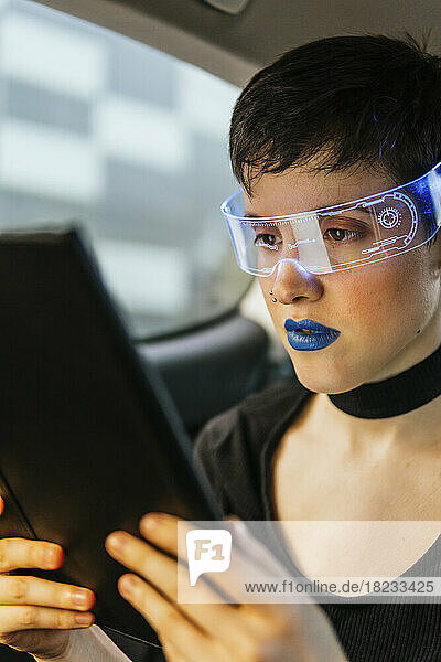 Woman wearing smart glasses using tablet computer in car