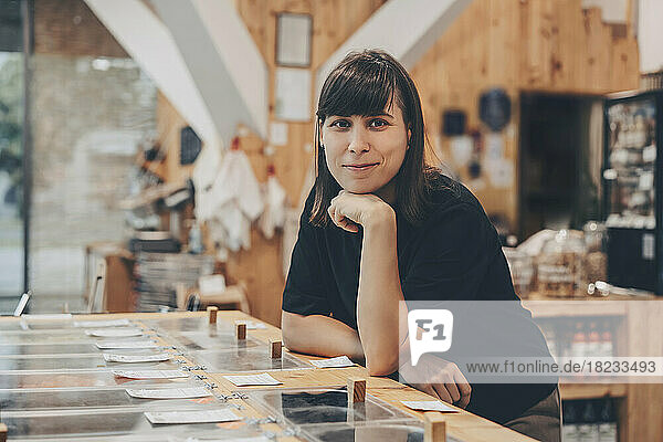 Smiling store owner leaning on counter in zero waste shop