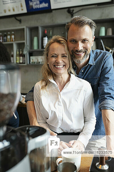 Happy coffee shop owner standing together at counter