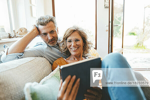 Älteres Paar sitzt mit Tablet-PC auf dem Sofa im Wohnzimmer