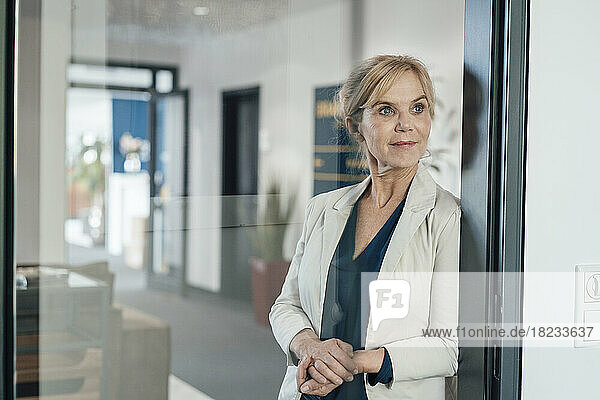 Thoughtful businesswoman in office seen through glass door