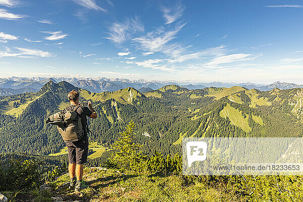 Germany  Bavaria  Male hiker admiring surrounding landscape from summit of Hirschberg mountain