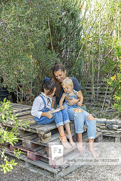 Family with book sitting on wooden pallet