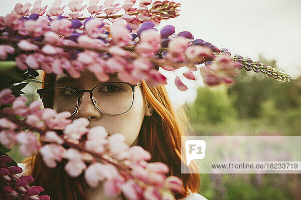 Teenager-Mädchen hält einen Strauß Lupinenblüten vor dem Gesicht