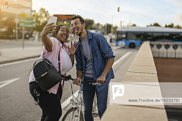 Glücklicher junger Mann und Frau  die am Fußweg ein Selfie mit dem Mobiltelefon machen