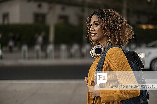 Junge Frau mit Rucksack und kabellosen Kopfhörern