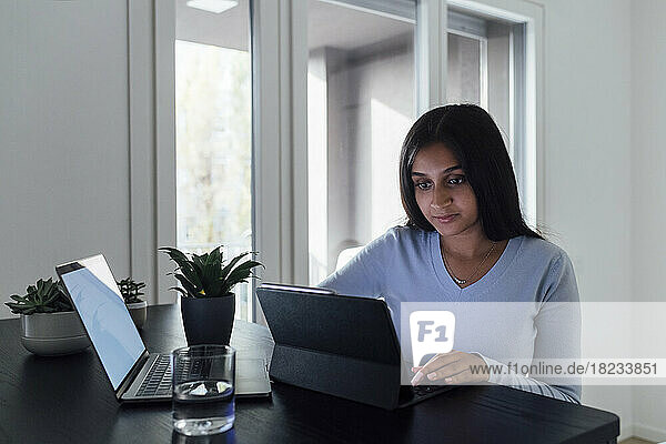Young woman studying through laptop at home