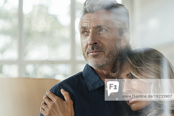 Mature woman hugging man seen through glass window