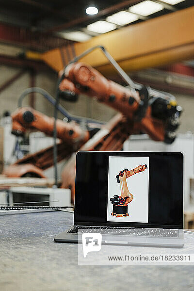 Laptop with robotic arm picture at desk in industry