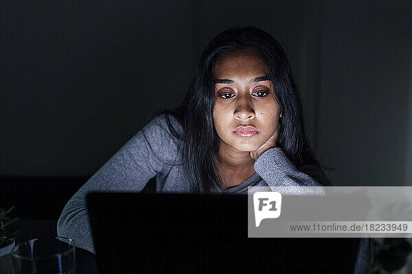 Junge Frau schaut zu Hause auf Laptop