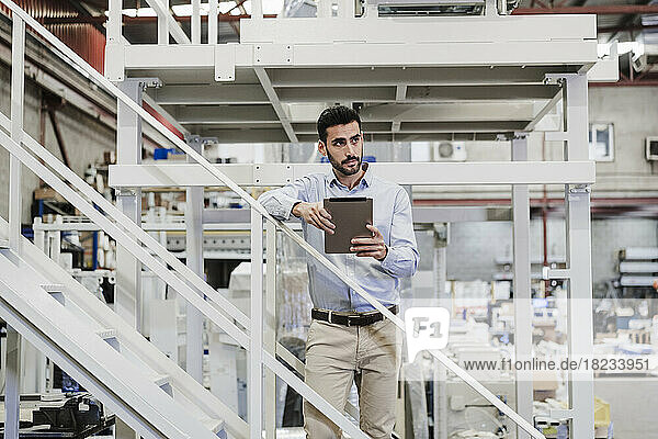 Nachdenklicher Geschäftsmann steht mit Tablet-PC auf der Treppe