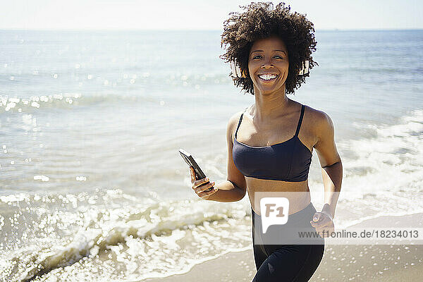 Happy young woman with smart phone at beach