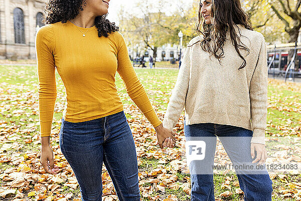 Woman holding hand of friend at autumn park