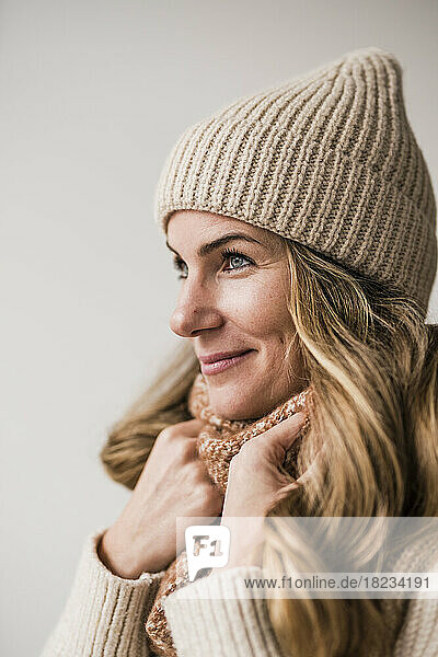 Smiling blond woman wearing knit hat against white background