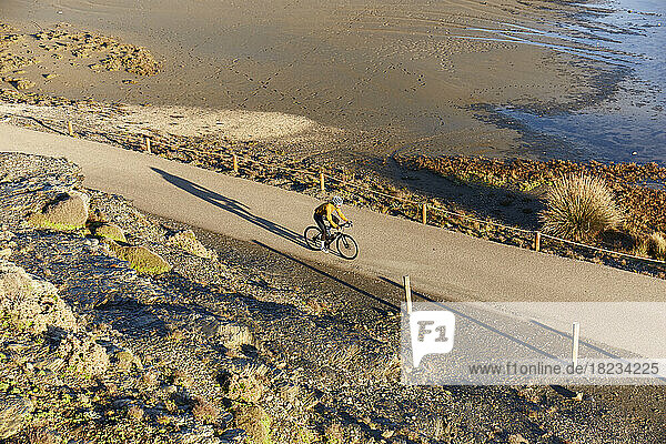 Cyclist riding bicycle by beach on sunny day