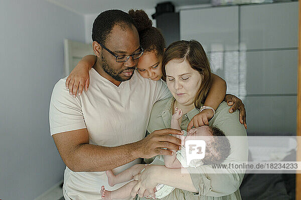 Family pampering crying baby girl at home