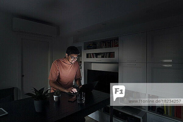 Smiling man using laptop in living room at home