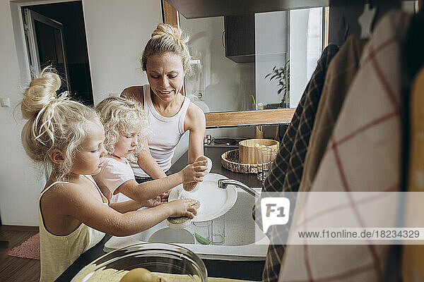 Woman with daughters washing dishes in the kitchen