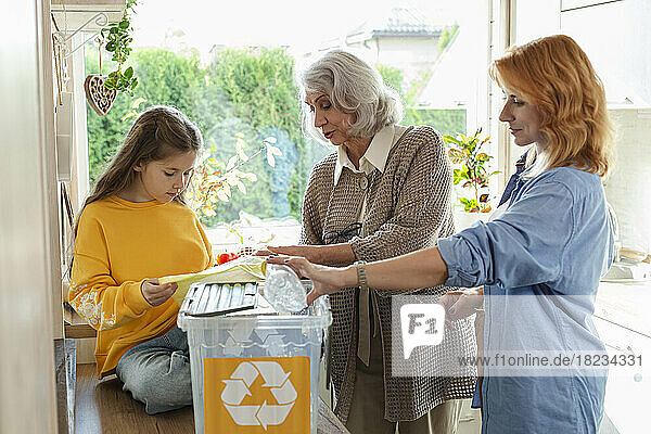 Großmutter  Mutter und Tochter sortieren Recyclingmüll in der Küche