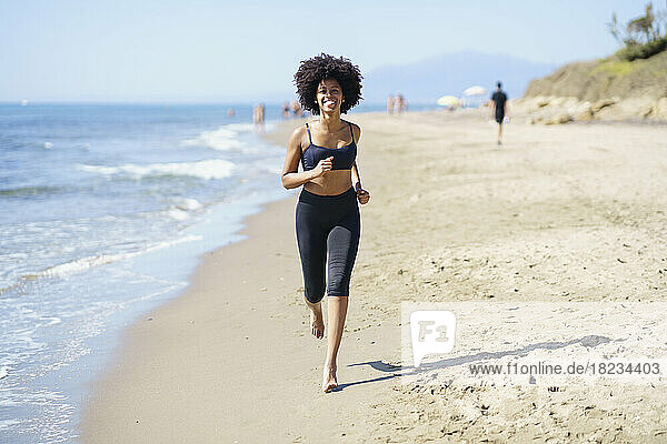 Happy young woman running on shore at beach