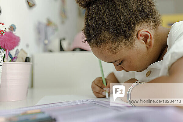 Girl drawing on paper at desk
